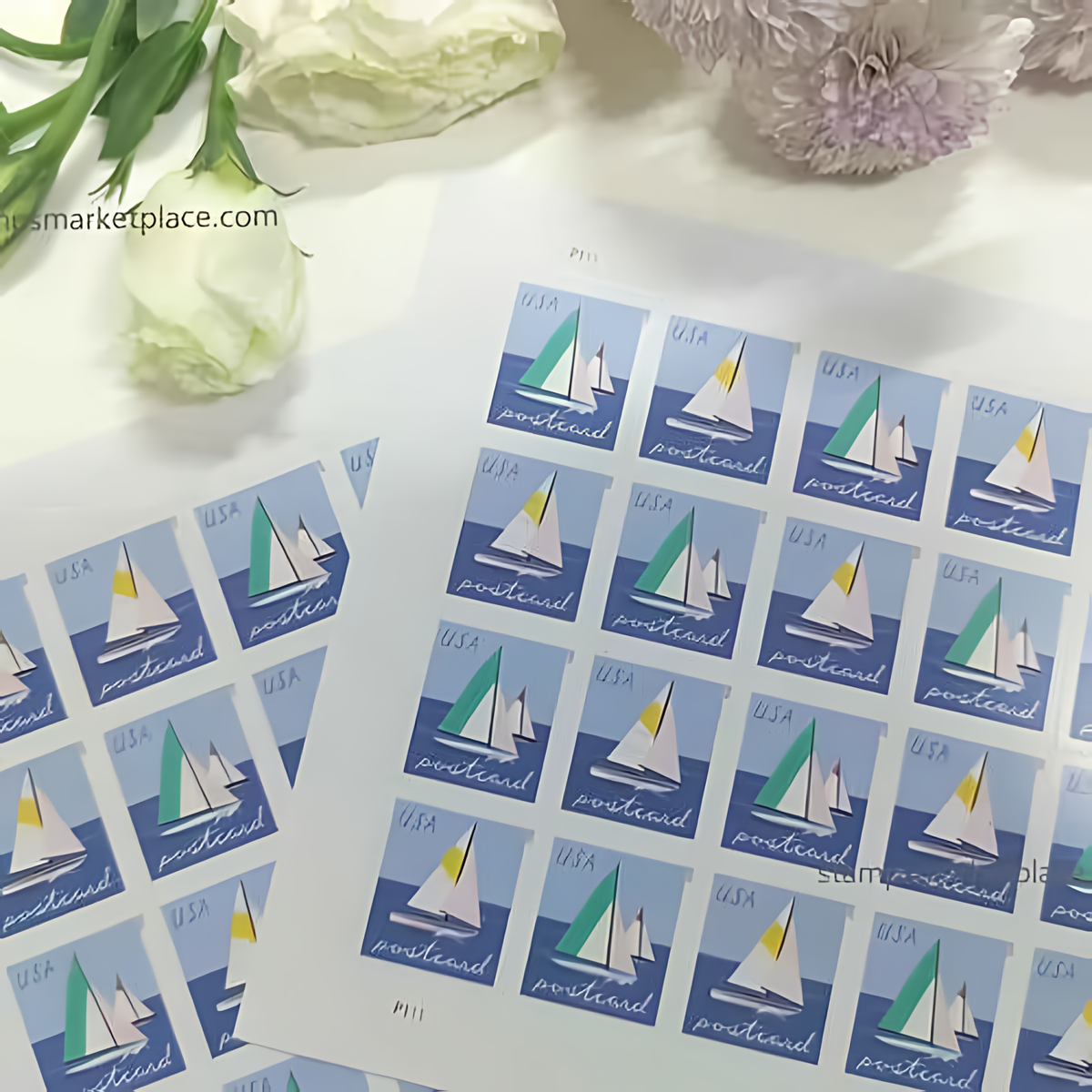 2023 Sailboats postcard stamp sheets beside white flowers